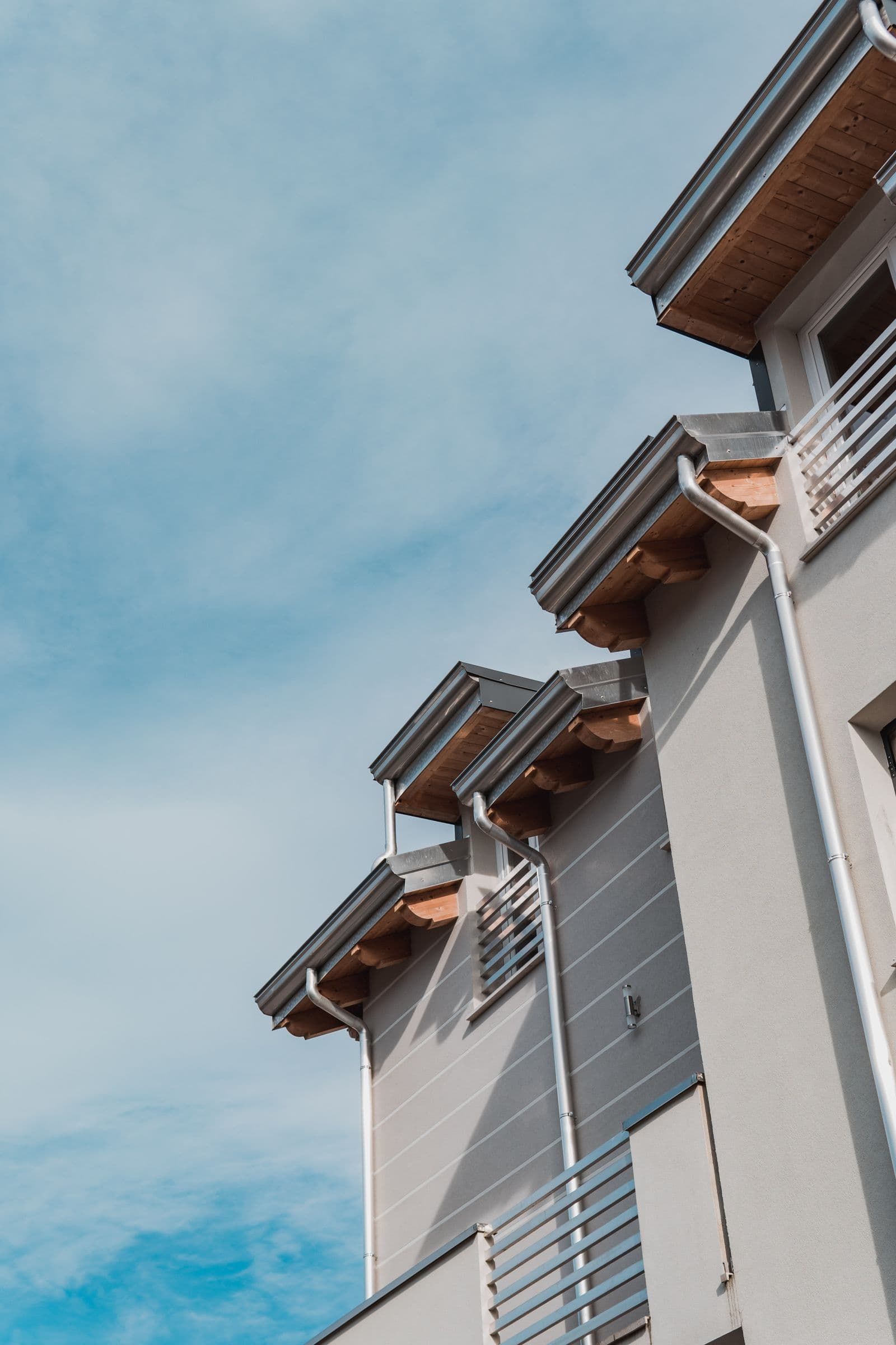 Clean gutters and downspouts running along a home's eaves against a blue sky.